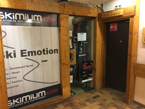 A wooden interior with a sign for 'Belle-donne' and a large advertisement for 'Skimium.com' featuring 'Ski Emotion' and 'Snowboard Rental.' - Bright apartment at the foot of the slopes - 4 guests (Les Menuires)