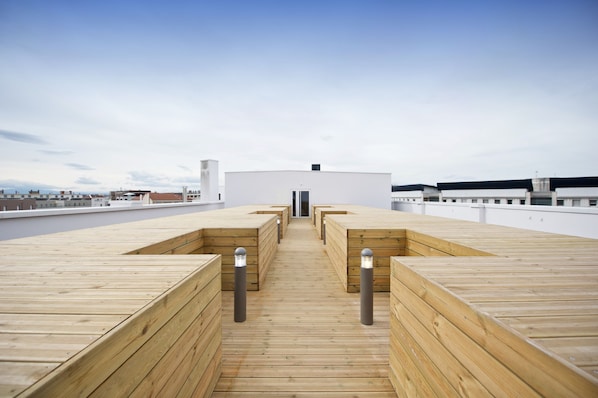 Un pont d'uns fustes amb bancs i un camí central que condueix a un edifici.