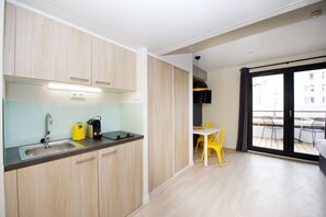 Cocina moderna con pileta, estufa y placares. Hay un comedor con mesa y sillas.