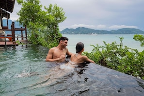 A couple in a private infinity pool with a view of a calm lake and distant mountains. - JA Enchanted Island Resort (Round Island)