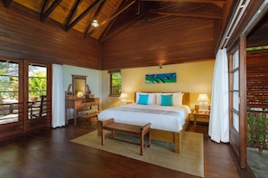 A wooden-paneled bedroom with a bed, bedside tables, a bench, and a view of greenery. - JA Enchanted Island Resort (Round Island)