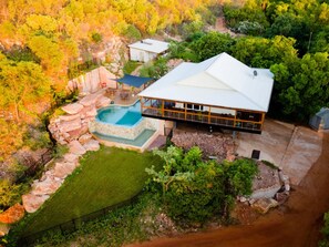 A large house with a swimming pool, surrounded by a natural landscape.