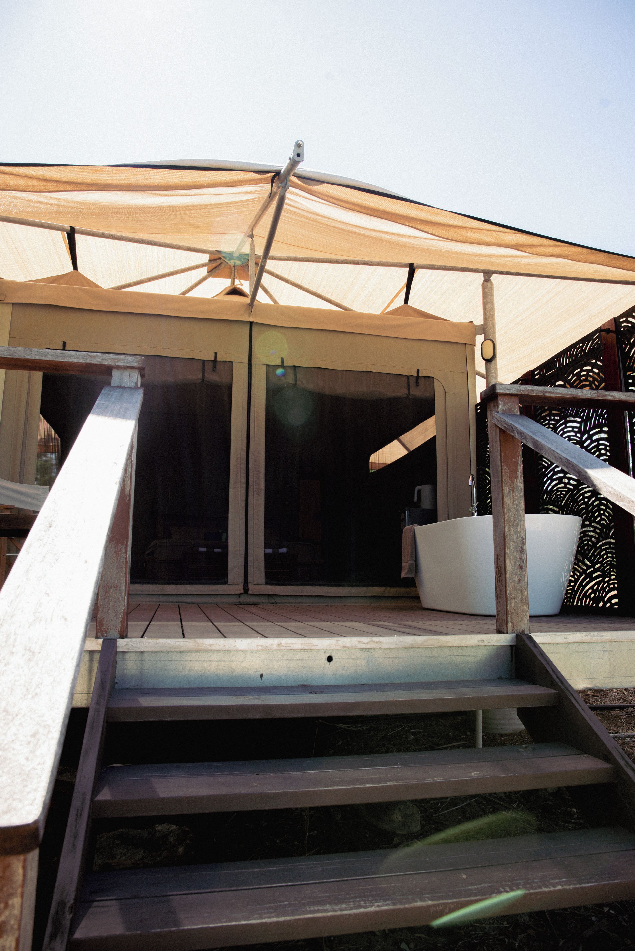 A wooden staircase leading to a covered outdoor area with a canopy.
