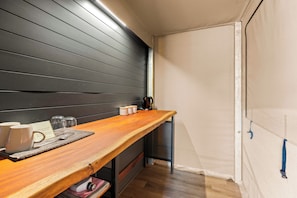 Una habitación pequeña con una mesa de madera, una tetera y algunas tazas.