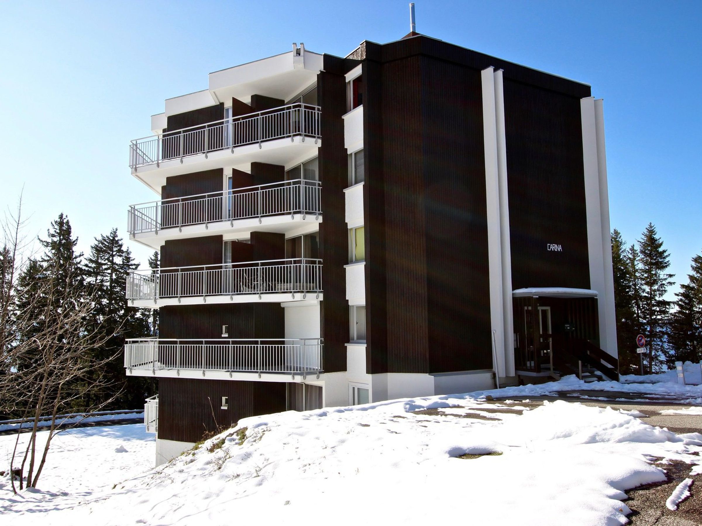 A multi-story building with balconies, a dark facade, and a sign reading "CARINA".