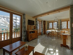 A spacious room with a dining area, a television, and a view of a snowy mountain. - Family house, parking, pets - 6 guests (Valloire)