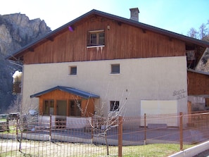 Un bâtiment en bois à deux étages, doté d’un toit en pente, d’un petit porche et d’une cour clôturée.