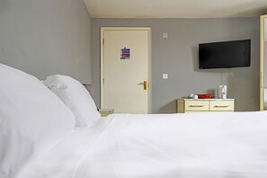 A hotel room with a bed, a television mounted on the wall, a door with a sign, and a small table with a coffee maker. - OYO The Billingford Horseshoes - Self Check IN (Diss)
