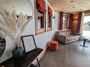 Ein Zimmer mit einer Couch, einem kleinen Tisch, einer Vase mit Pampasgras und einem gerahmten Zitat an der Wand.