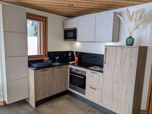 A compact kitchen with wooden cabinets, a microwave, a sink, and a stove. - Apartment in Les Gets with private parking - 4 guests (Les Gets)