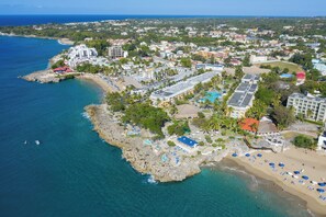 An aerial view of a coastal resort with multiple buildings, a beach, and a swimming pool area. - Casa Marina Beach Reef (Sosúa)