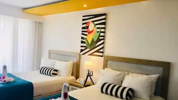 Quarto de hotel com duas camas, cada uma com almofada listrada e manta azul-esverdeada. Há uma obra de arte na parede acima das camas e uma mesa de cabeceira com abajur e telefone.