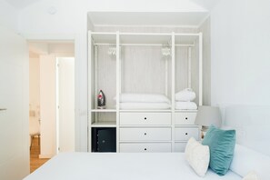 Ein Schlafzimmer mit Bett, Nachttisch, Lampe, Kleiderschrank und kleinen Stauraum.