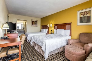 A hotel room with two beds, a desk with a computer and phone, a chair, and a couch.