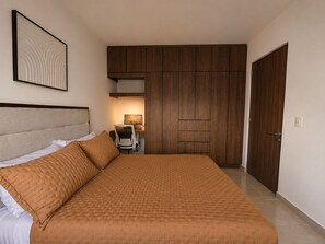 A bedroom with a large bed, a desk, and a wardrobe. - Nómada Living | 2 bedrooms, pool, and excellent location (Zaru)
