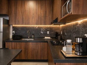 Una cocina moderna con armarios de madera, encimera negra, microondas integrado y cocina a gas.