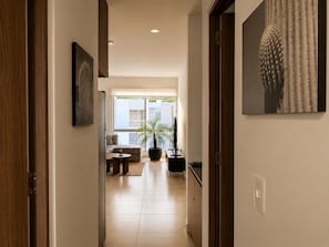 Un pasillo que conduce a una sala de estar con un sofá, una mesa de centro y una planta en maceta.