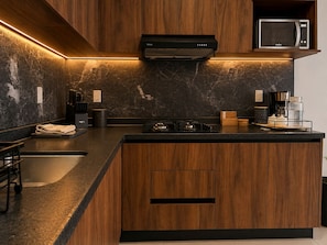 A modern kitchen with a central island, built-in microwave, and a range hood. - Nómada Living | 2 bedrooms, pool, and excellent location (Zaru)