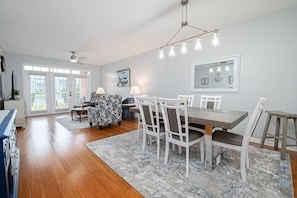 A spacious dining area with a large table and chairs, a ceiling fan, and a chandelier. - Seaside at Anastasia B104 Condo (St. Augustine)