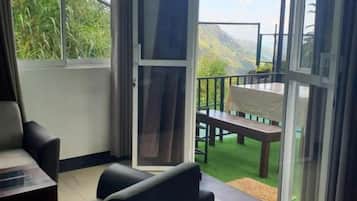 A room with a sliding glass door leading to an outdoor area with a bench and a table.