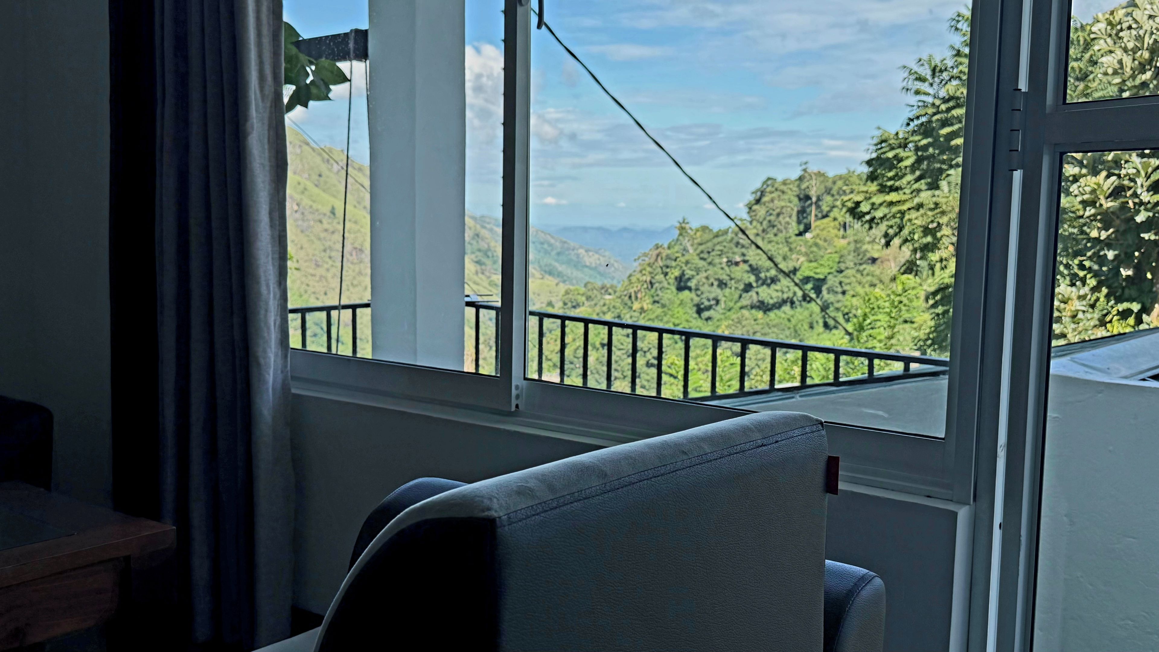 Ein Zimmer mit Blick auf eine gebirgige Landschaft durch ein Fenster mit schwarzem Metallgitter.
