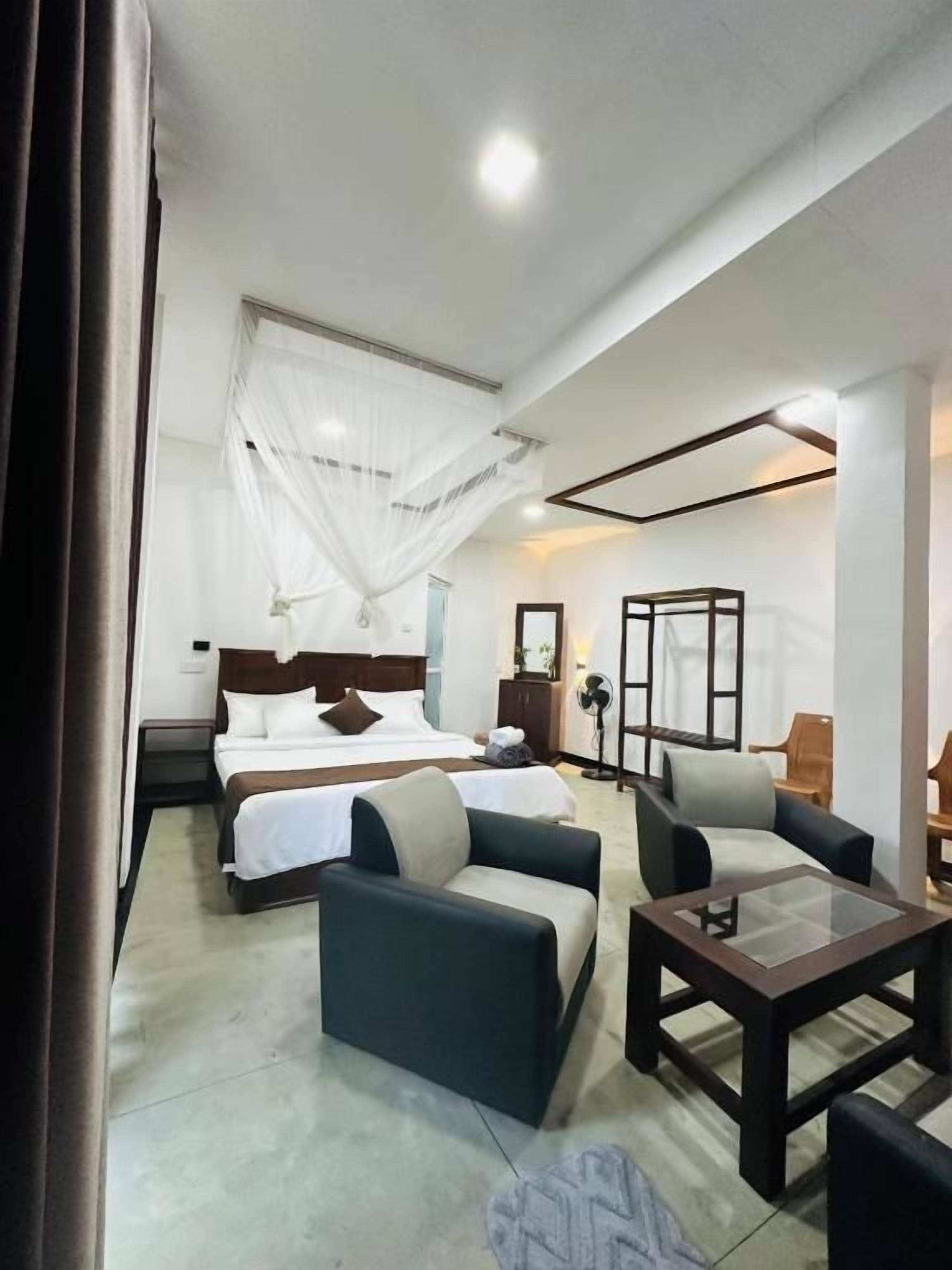 Una habitación de hotel con una cama, dos sofás, una mesita de centro y una mesita de noche.
