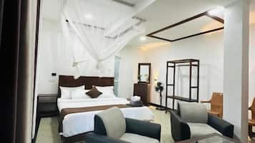 Una habitación de hotel con una cama, dos sofás, una mesita de centro y una mesita de noche.