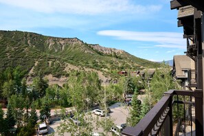 A mountainous landscape with a residential area, including houses and a road. - Luxury One Bedroom, Capitol Peak, Base Village steps away from lifts. (Snowmass Village)