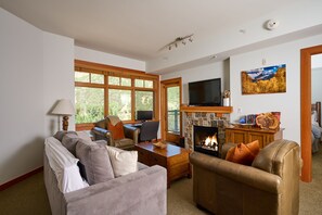 A living room with a fireplace, a television, and a large window. - Luxury One Bedroom, Capitol Peak, Base Village steps away from lifts. (Snowmass Village)