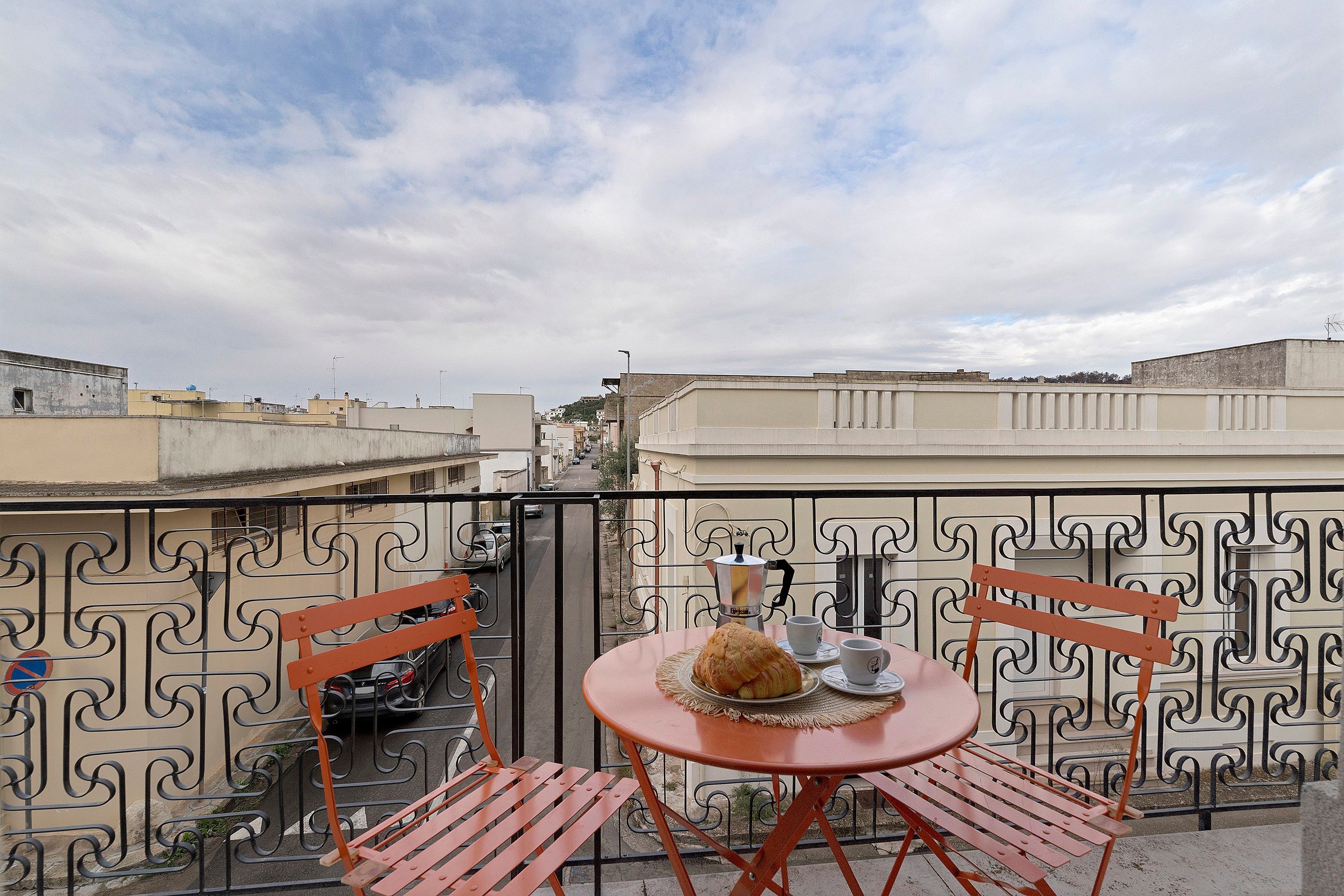 Ein Balkon mit Tisch für zwei Personen, einer Kaffeekanne und einem Gebäck.