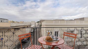 Ein Balkon mit Tisch für zwei Personen, einer Kaffeekanne und einem Gebäck.
