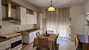 A compact kitchen with a dining area, a built-in oven, and a hanging light fixture.