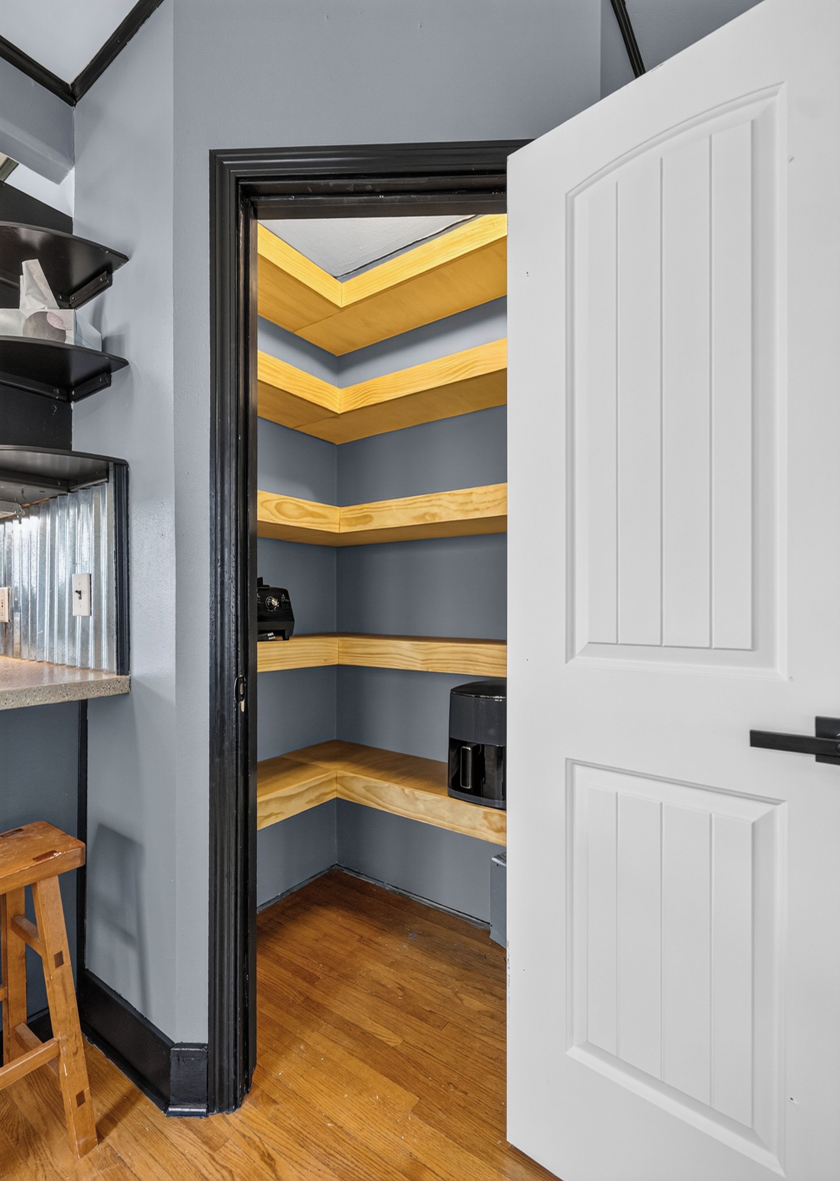 A narrow hallway with wooden shelves and a coffee maker on one of the shelves.