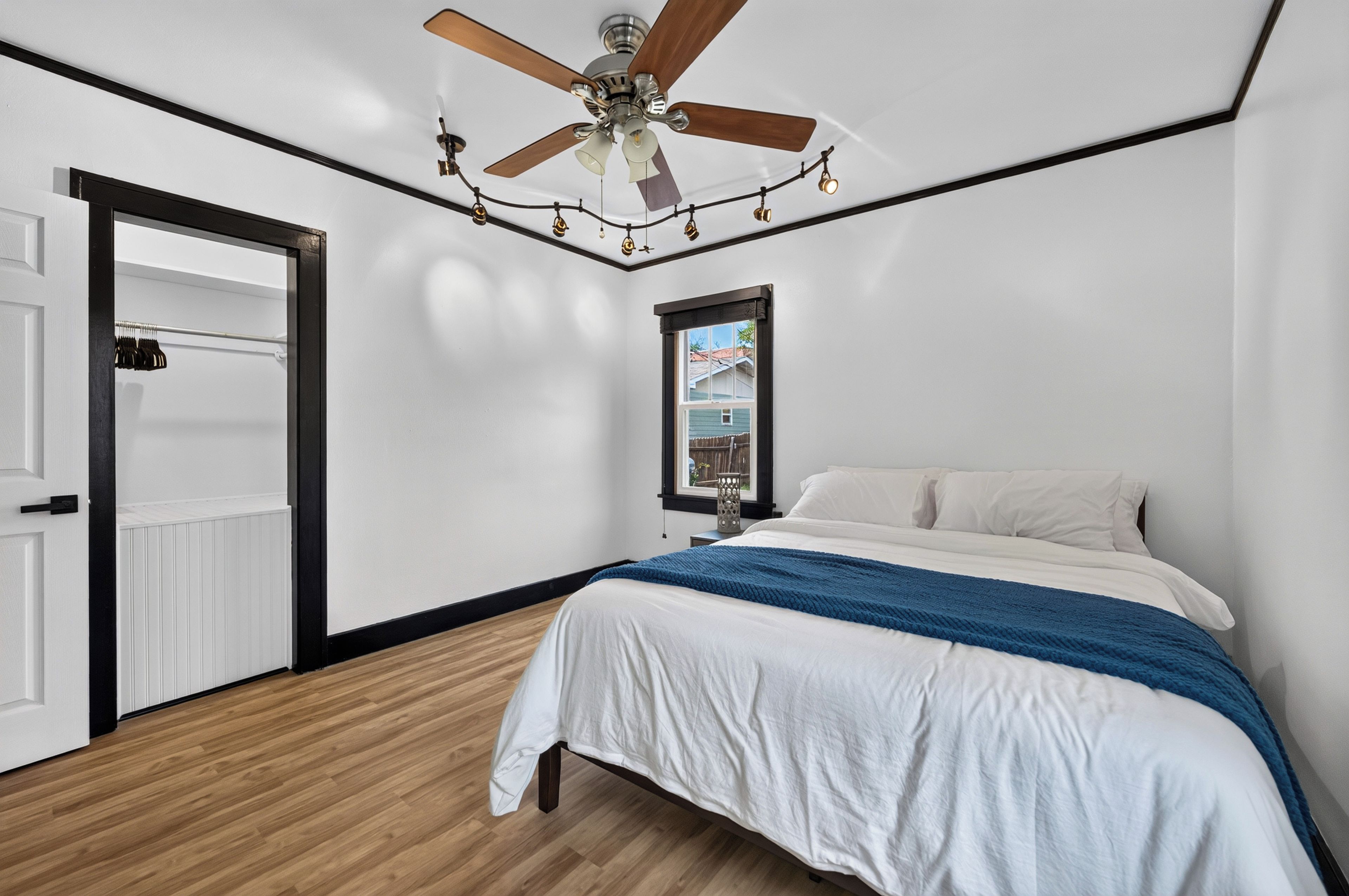 A bedroom with a bed, a ceiling fan, a window, and a door.