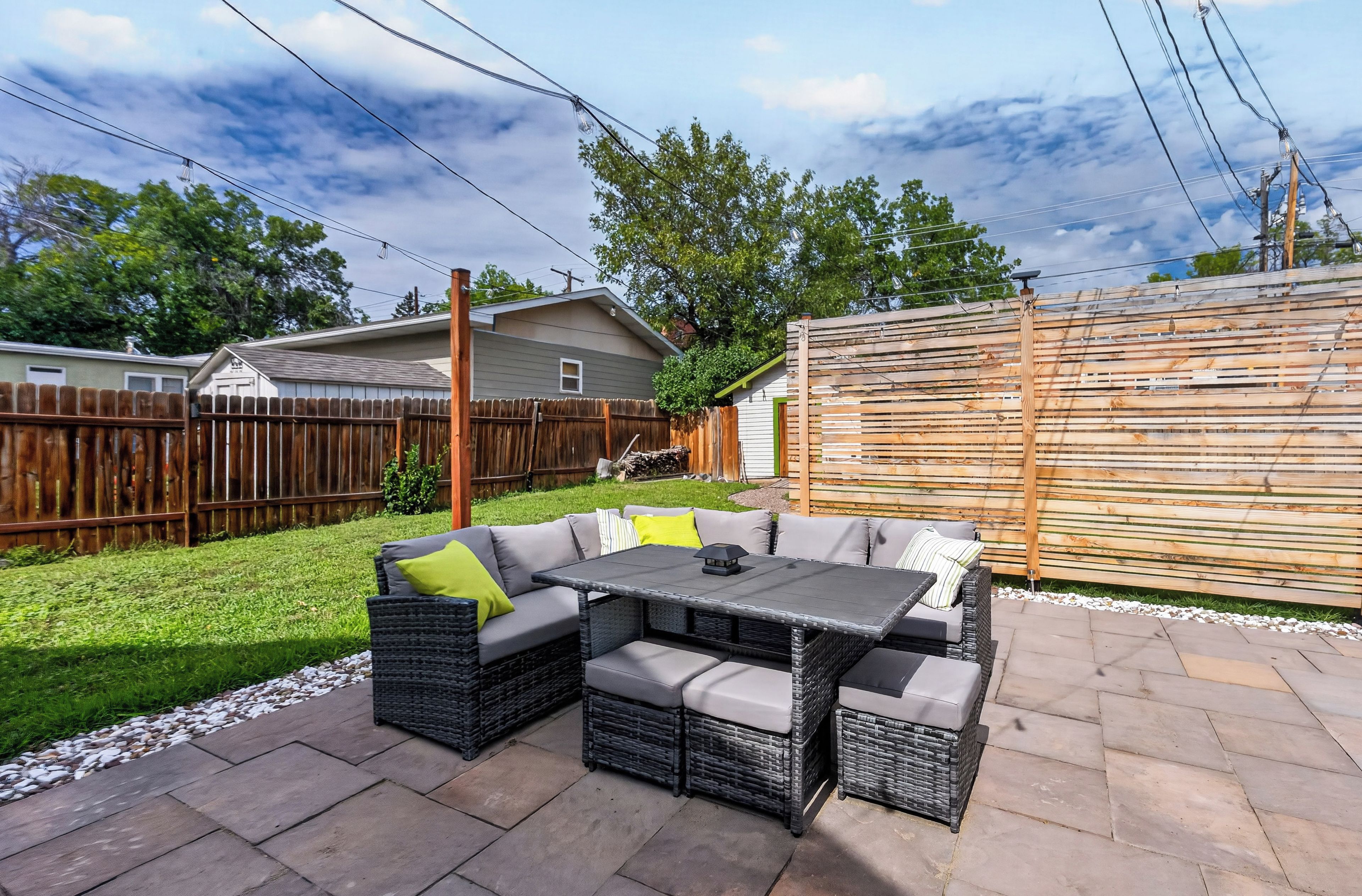 Un patio al aire libre con un sofá modular, una mesa y una valla de madera.