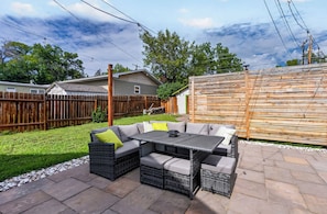 Um pátio externo com um sofá modular, uma mesa e um cercado de madeira.