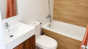 Casa de banho com lavatório branco, sanita e banheira.