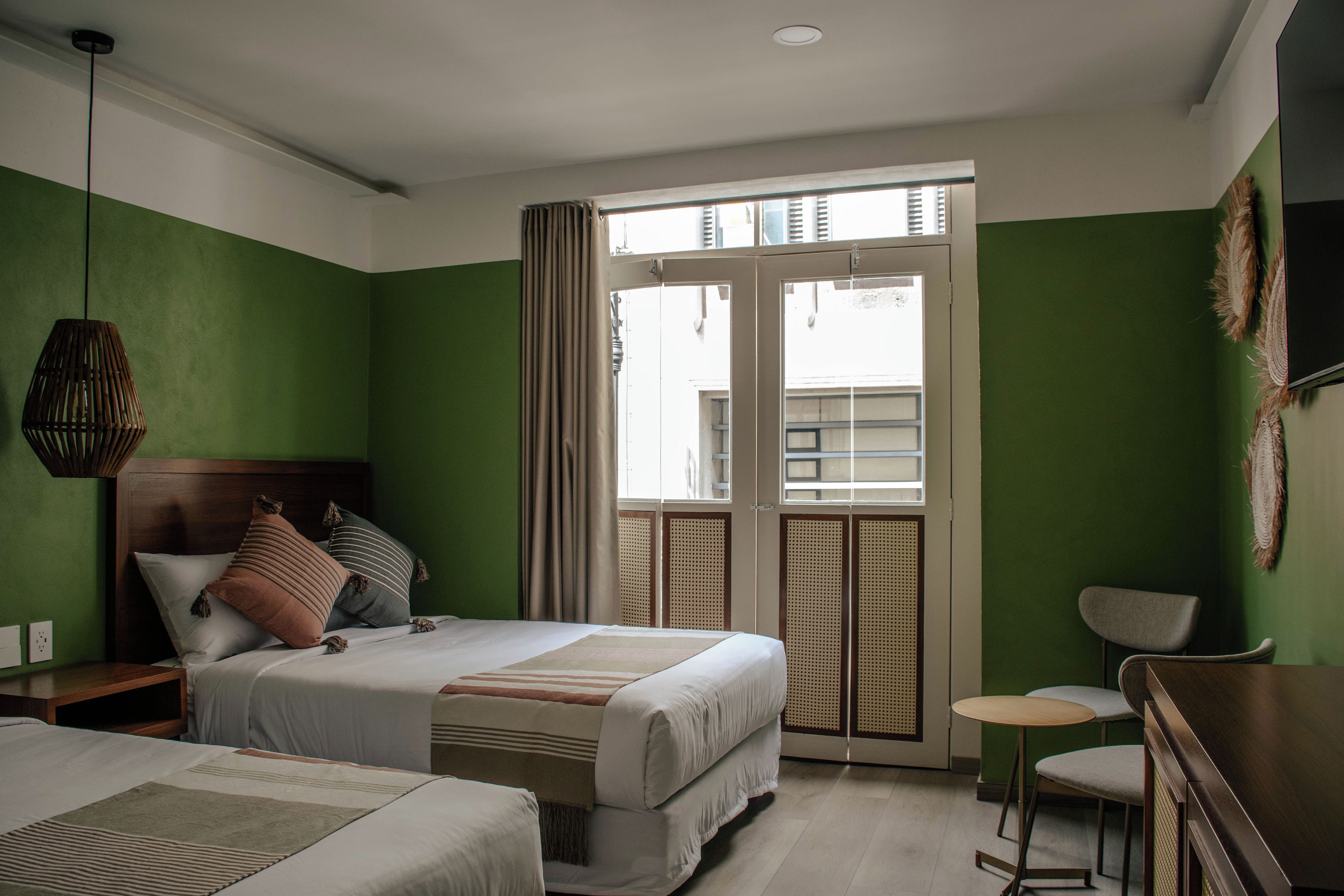 Una camera d'albergo con un letto, una scrivania e una sedia. C'è una finestra con tende.