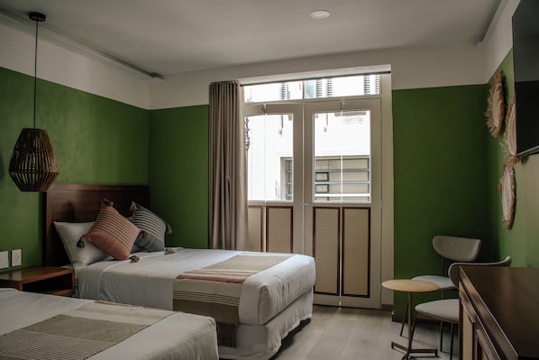 A hotel room with a bed, a desk, and a chair. There is a window with curtains.