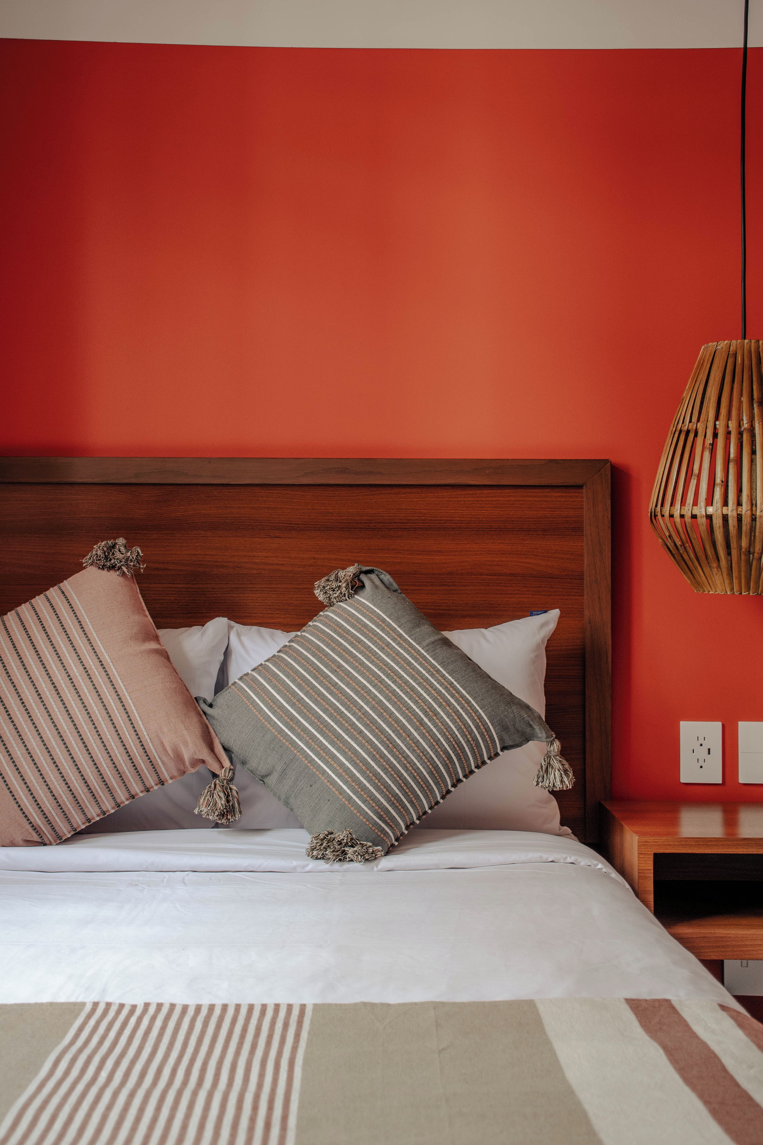 A bed with a wooden headboard, two pillows, a bedside table, and a hanging light fixture.