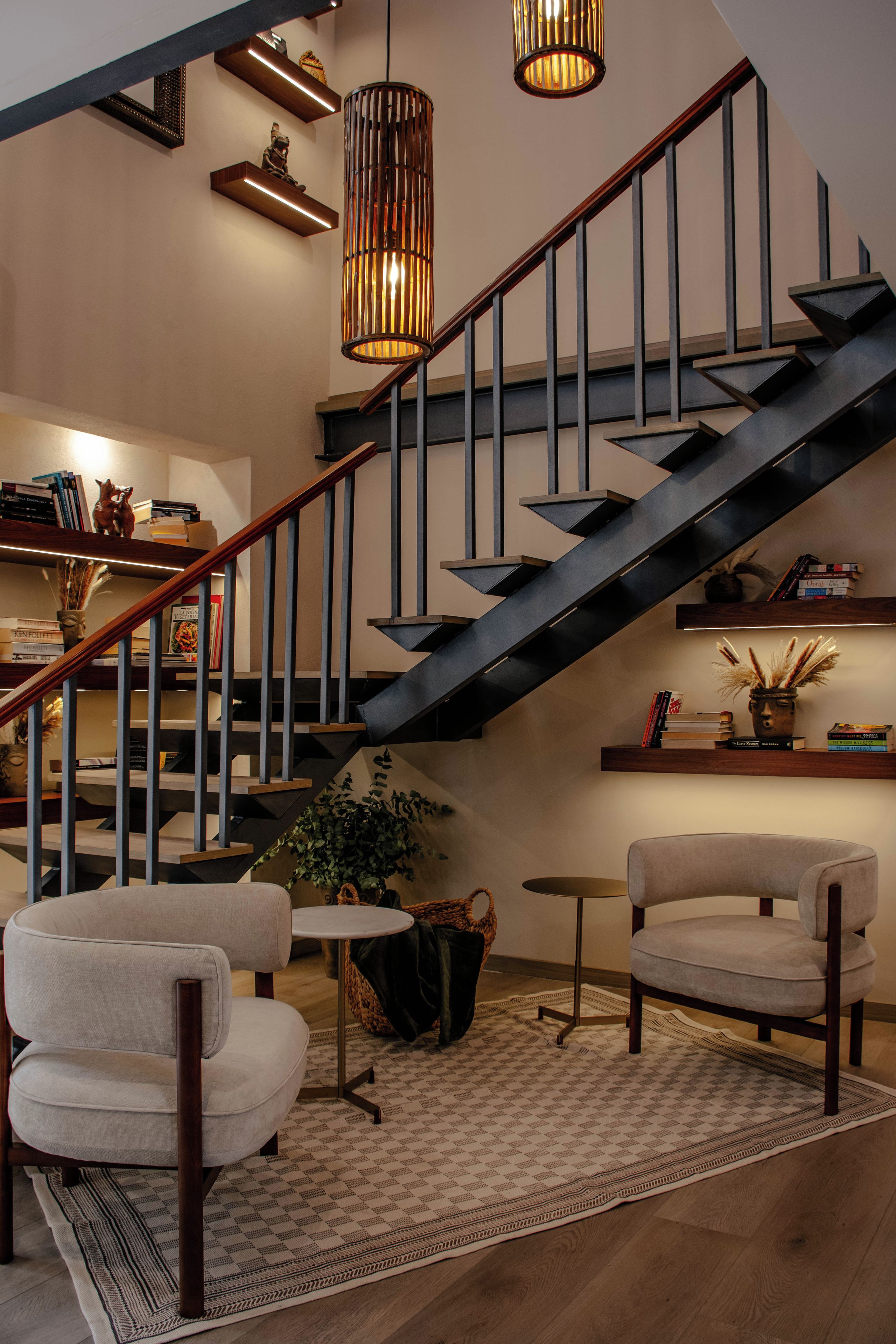 A modern interior with a staircase, bookshelves, and seating area.
