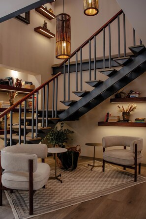 A modern interior with a staircase, bookshelves, and seating area.