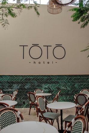 A TOTO hotel sign with a modern design, surrounded by outdoor seating with checkered chairs and a herringbone patterned wall.
