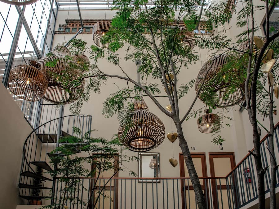 Un atrium à plusieurs niveaux, agrémenté de luminaires sphériques suspendus et d’un escalier.