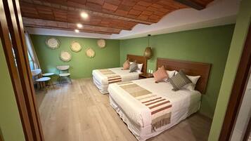 Una habitación con dos camas, una mesita y sillas.