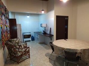 A compact kitchen with a gas stove, oven, and a small dining area with a round table and chairs. - Beach house in Picinguaba, Beach house, House in Ubatuba, House in Picinguaba. (Ubatuba)