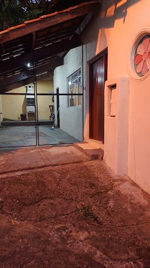 A covered outdoor area with a concrete floor, a metal gate, and a building entrance with a door. - Beach house in Picinguaba, Beach house, House in Ubatuba, House in Picinguaba. (Ubatuba)