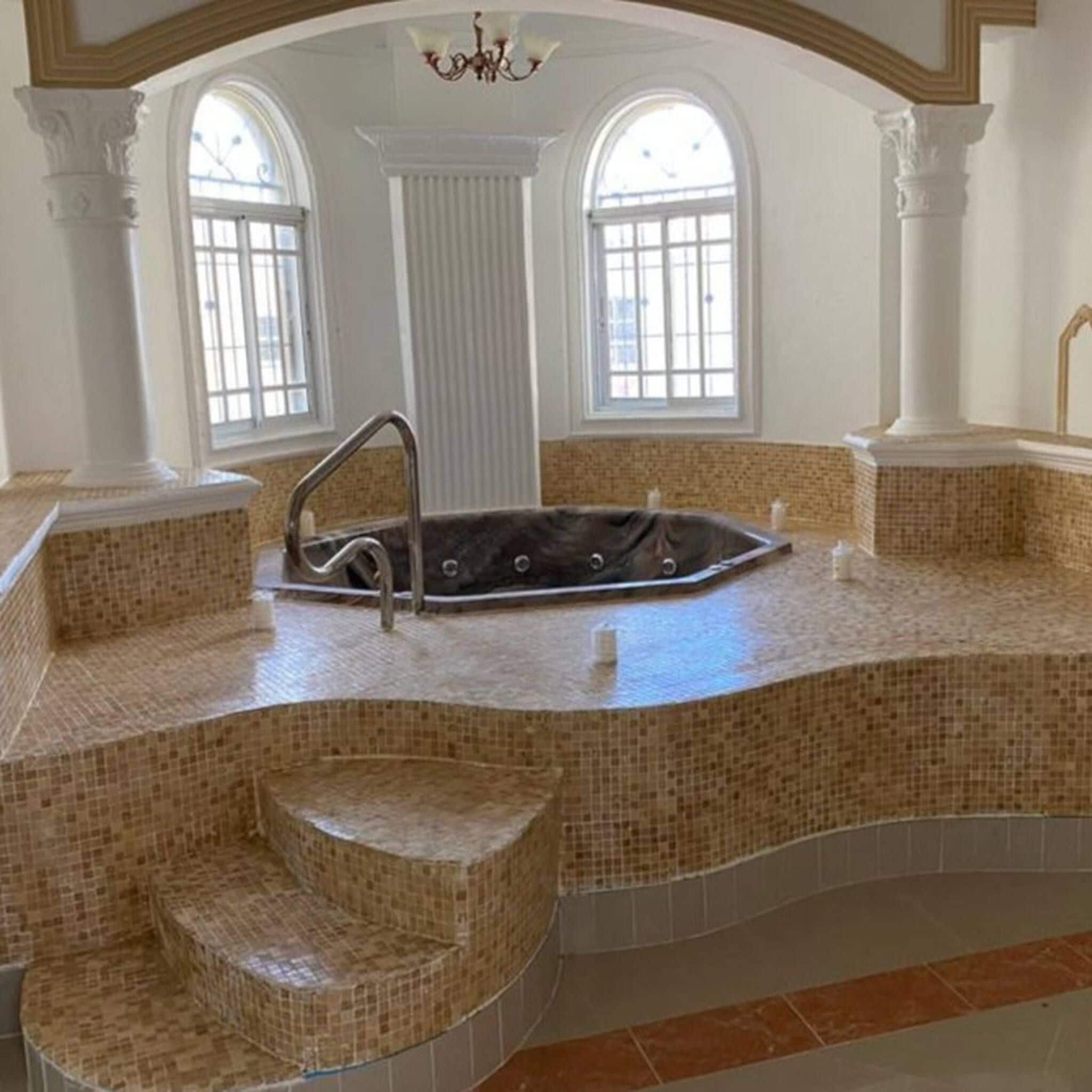 A spa area with a hot tub, steps, and large windows.