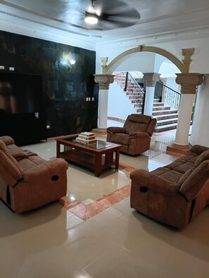 A spacious living room with a modern design, featuring a large black wall, a glass coffee table, and two brown leather sofas. - Luxurious Colonial Mansion in Puerto Plata With Private Pool (Puerto Plata)