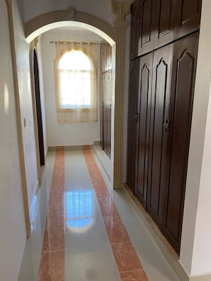 A hallway with a tiled floor, a window with curtains, and a set of dark wooden cabinets. - Luxurious Colonial Mansion in Puerto Plata With Private Pool (Puerto Plata)